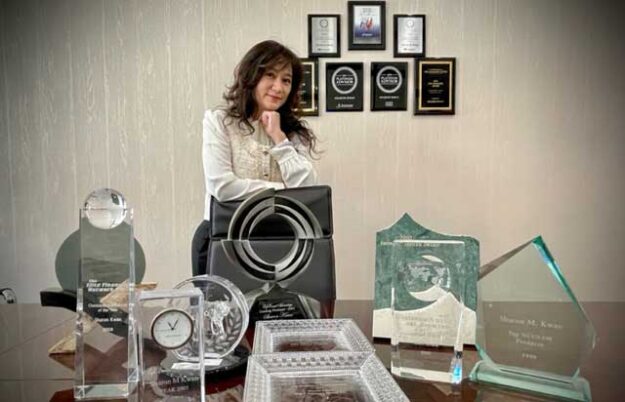 Sharon Kwan standing in front a table with her awards and accomplishments laid out on the table